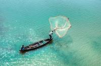 Urban communities including fishing communities face climate risks. A fisherman on a boat casts a net upon wide waters.