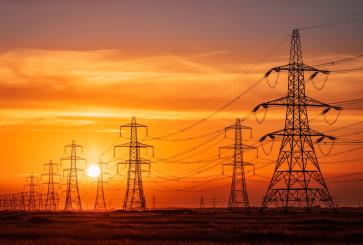 Pylons and electrical supply lines with a flaming sunset background