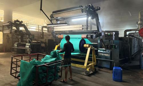 Factory worker in a Textil MSME collects cloth from a big drum.