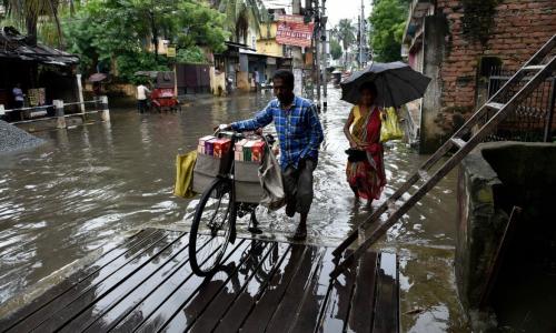 Commuters wade through flooded streets after heavy rainfall in Guwahati, Assam. Photo by Shutterstock.