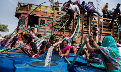 Residents climb on a municipal water tanker to fill their containers. Photo by Manoej Paateel/Shutterstock